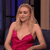 a woman in a pink dress is sitting on a blue couch