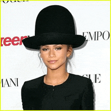a woman wearing a large black hat and a black jacket .