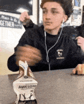 a young man is sitting at a table with a carton of awesome milk on it .