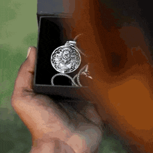 a person is holding a silver necklace in a black box