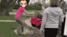 a girl is pushing a red toy car in a park while a boy stands behind her .