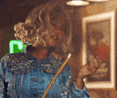 the woman is wearing a denim jacket and holding a pool cue .