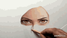 a person is drawing a woman 's eyes with a pencil