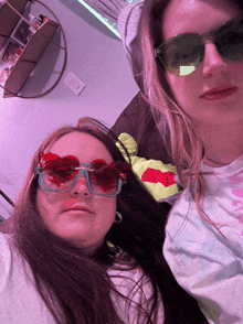 two girls wearing heart shaped sunglasses are posing for a picture