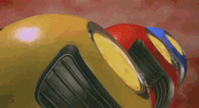 a yellow object with a red and blue object in the background
