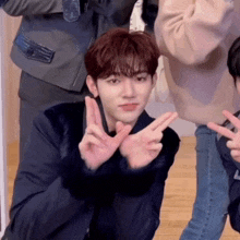 a young man in a black jacket is making a peace sign with his hands .