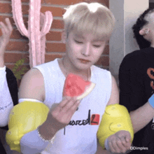 a young man is eating a slice of watermelon while wearing yellow elbow pads