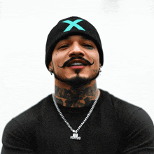 a man wearing a black shirt and a black beanie with an x on it