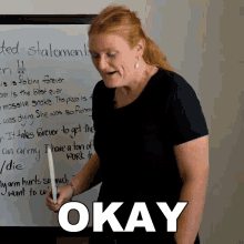 a woman stands in front of a white board with the word okay on it