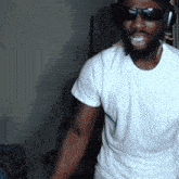 a man wearing sunglasses and a white shirt is smiling