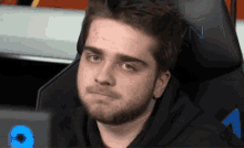a man with a beard is sitting in a black chair with the number 1 on it