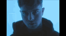 a close up of a man 's face in a dark room with a blue light behind him .