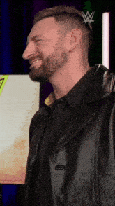 a man with a beard wearing a black shirt and black leather jacket