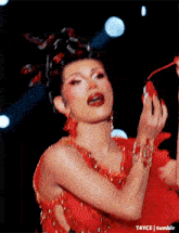 a woman in a red dress is holding a red fan in her hands .
