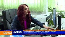 a woman sits at a desk in front of a computer screen that says jutro on the bottom