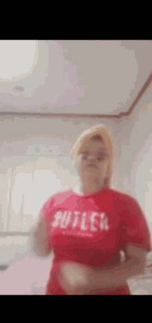 a woman is wearing a red shirt that says ' butler ' on it