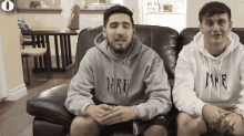 a man wearing a grey dare hoodie sits next to a man wearing a white dare hoodie