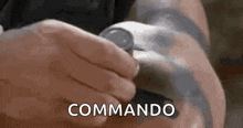 a person is holding a can of soda in their hand and the word commando is written on the screen .