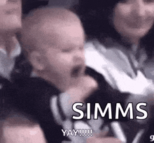 a baby is screaming in a crowd of people while being held by a woman in a stadium .