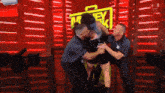 three men are holding a woman in front of a sign that says ' money in the bank '
