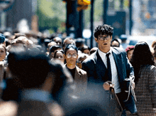a man in a suit and tie is walking through a crowd