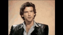 a man with long hair is wearing a black leather jacket and striped shirt .