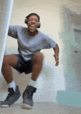 a man wearing headphones is jumping in the air with his legs crossed