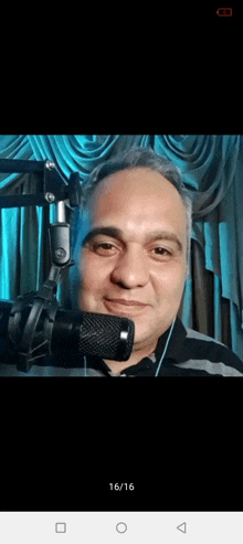 a man is smiling in front of a microphone with the date 16/16 on the bottom right