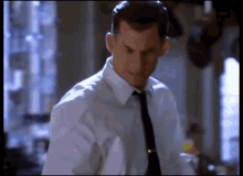 a man in a white shirt and black tie looks down