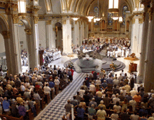 a large crowd of people are gathered in a church with a cat on the stage