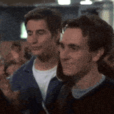 two young men are standing next to each other in a crowded room and smiling .