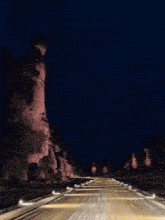 a road that is lit up at night with a rock in the background