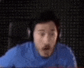a man wearing headphones and a blue shirt is sitting at a desk .