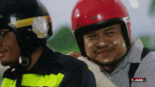 a man wearing a red helmet is standing next to another man wearing a black helmet