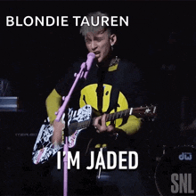 blondie tauren is playing guitar and singing into a microphone
