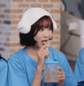 a woman in a blue shirt drinking from a blue bottle with a straw