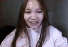 a close up of a woman 's face with her mouth open and a white shirt on .