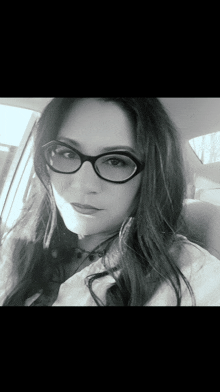a black and white photo of a woman wearing glasses and a white shirt