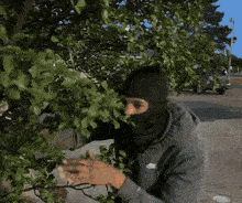 a man wearing a black nike hoodie is standing in front of a tree