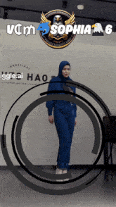 a woman in a blue jumpsuit is standing in front of a sign that says sophia on it