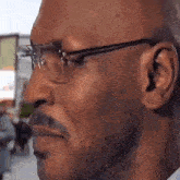 a man with glasses and a mustache is looking at something .
