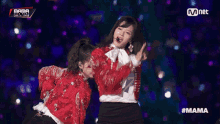 a woman in a red sequined jacket stands next to another woman in a white shirt and black skirt