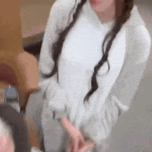 a woman in a white sweater is standing next to a man in a chair and pointing at him .