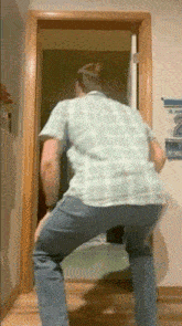 a man in a plaid shirt is dancing in a doorway