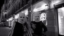 a black and white photo of two people wearing ski masks in front of a luxbag store