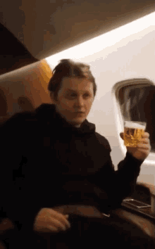a man in a black hoodie is holding a glass of beer in his hand