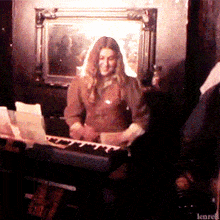 a woman is playing a keyboard in a dark room with the word lenre on the bottom right