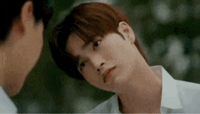 a man in a white shirt is looking at another man in a mirror .