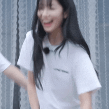 a woman in a white t-shirt is laughing and holding a man 's hand .