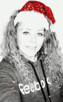 a woman wearing a santa hat and a grey reebok hoodie